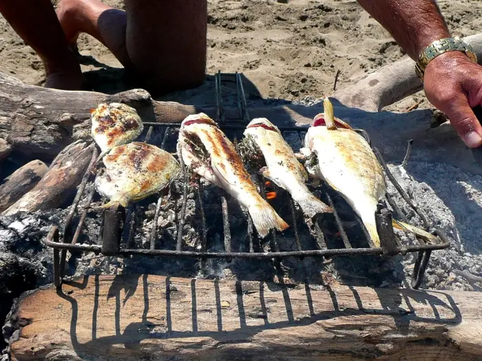 Whole fish grilling over glowing charcoal on a wire rack