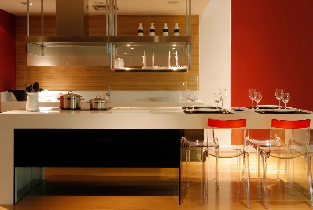A kitchen island with a glowing underside and a warm timber wall