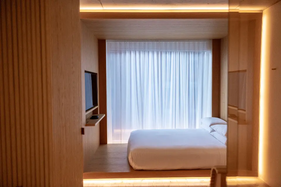 A timber-lined bedroom with a glowing cove around the bed