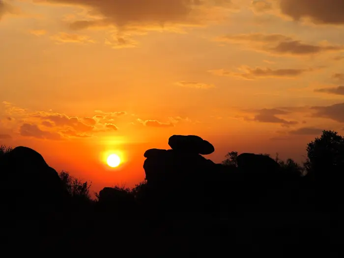 Granite kopje boulders silhouetted against an orange Serengeti sunset