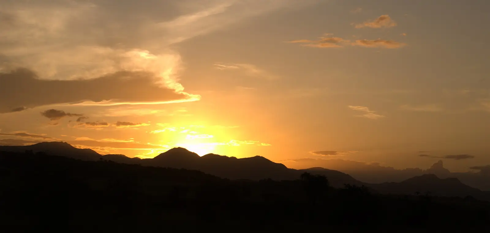 Golden grassland and hills under a sunset sky in a wide valley