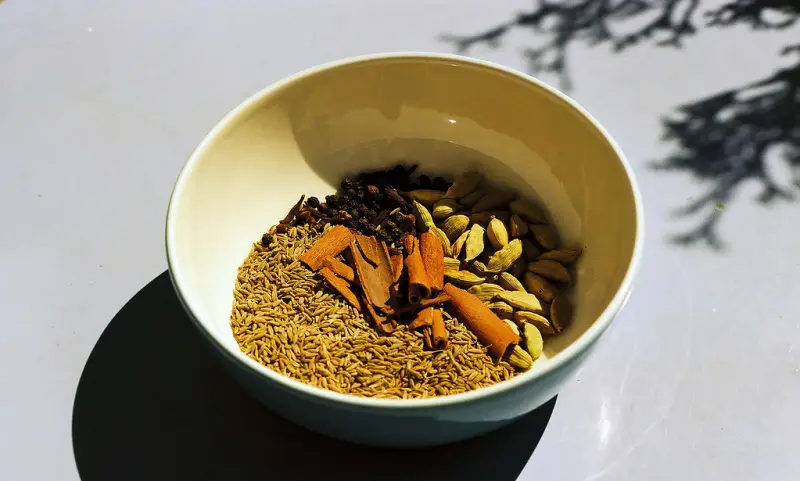 Cloves, cinnamon sticks, cardamom and cumin in a bowl in the sun