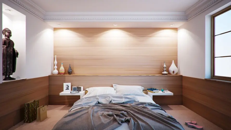 A short-let bedroom with a warm timber wall and downlights